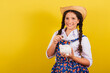 Girl wearing typical clothes for Festa Junina. Holding coin and piggy bank. For the Arraia party