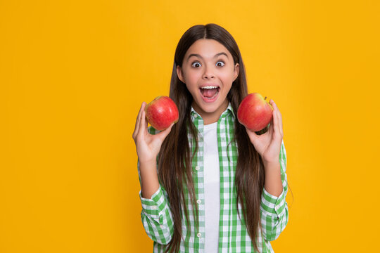 amazed child with fresh apple on yellow background