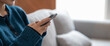 © Natee Meepian - Close up of a woman using mobile smart phone on sofa at cozy home