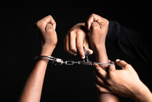 Close Up Shot Of Hands Removing Cuffs From Hand On Black Dark Background - Concept Of Freedom, Releasing And Liberty.