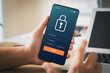 © Thapana_Studio - Cybersecurity internet and networking concept. Close up of hand holding smartphone information security and encryption, secure access to user's personal information, secure Internet access.