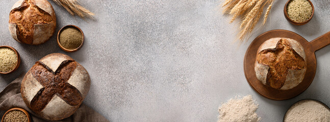 Banner of homemade freshly baked whole grain and hemp bread on gray background. View from above. Copy space.