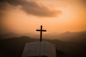 Christian Praise open bible and holy cross on the hill as background. Love to study the biblical concepts of Christianity.