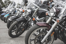 Motorcycles Parked In A Line In A Motorcycle Parking Lot. Close-up Of The Front Wheel Of A Motorcycle