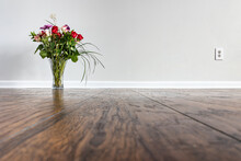 Roses Flower Arrangement Placed On The Floor Of An Empty Room Next To A Wall With A Baseboard And Power Outlet