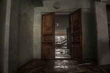 Dark Abandoned Room. Opened Door. Shabby Walls. Light In The Windows In The Background. Wooden Old Door In An Abandoned Building.