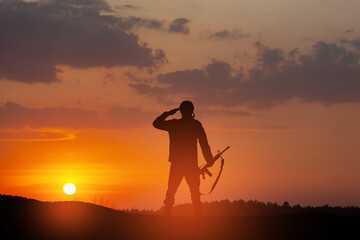 Silhouette of soldier standing against the backdrop of a sunset. Greeting card for Veterans Day, Memorial Day, Independence Day. USA celebration. Concept - patriotism, protection, remember honor.