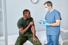 Mature Male Nurse Giving Recommendations To Young Black Soldier After Giving Him Vaccine Injection Against Coronavirus