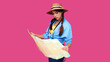 © khmelev - Smiling girl teen student in casual clothes and straw hat, backpack and digital camera holding map isolated on pink background. Female positive traveler. Caucasian tourist