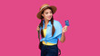 © khmelev - Young caucasian female buyer holding credit card and smiling on pink isolate background