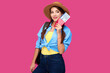© khmelev - Smiling woman traveler in straw hat and backpack holding passport with plane ticket over pink isolate background