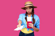 © khmelev - Young upset woman tourist with passport giving flight ticket. Caucasian traveler in summer casual clothes in pink isolated background. Female student with document