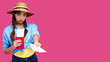 © khmelev - Young upset woman tourist with passport giving flight ticket. Caucasian traveler in summer casual clothes in pink isolated background. Female student with document