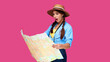 © khmelev - Smiling girl teen student in casual clothes and straw hat, backpack and digital camera holding map isolated on pink background. Female positive traveler. Caucasian tourist