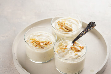 Wall Mural - Creamy dairy yoghurt dessert with mascarpone, cream cheese and peanut butter in glasses on concrete tray with a tea spoon