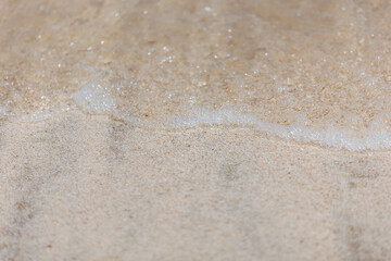Poster - Soft wave of blue sea on sandy beach. Background. Selective focus.
