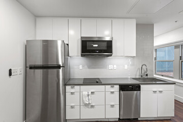 White apartment kitchen with black counter tops and white cabinets in city apartment