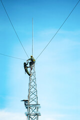 Silhouette electrician work installation of electricity lines in high voltage stations safely and systematically over blue sky background. Manual labor and industrial concept.