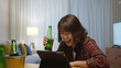 © ChayTee - Young happy attractive asia female enjoy relax night party event online celebration festive with friends at home sofa couch clinking beer with glass and bottle drinking via online video call.