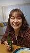 © ChayTee - Selfie view of young happy attractive asia woman enjoy relax night party event online celebration festive with friends at home clinking beer cheers with bottle toasting drinking via online video call.