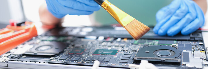 Poster - Man in gloves with a paintbrush cleans laptop parts