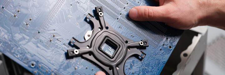 A man holds a motherboard over a pc, close-up