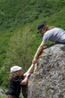 © Chepko Danil - Two people climbing on mountain and helping. children in the mountains help to climb.
