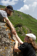 © Chepko Danil - Two people climbing on mountain and helping. children in the mountains help to climb.