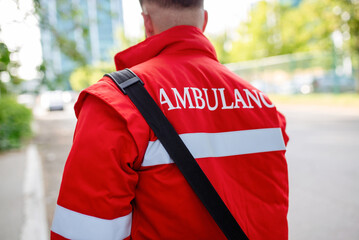 Wall Mural - Ambulance staff member from the back with his emergency backpack , and vital signs monitor. Ambulance written on his back.