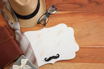 Wall Mural - Father's day concept. bow tie, fedora hat, glasses, old photo camera and funny moustache over wooden background. top view, flat lay