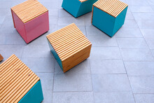 Group Of Empty Pink And Blue Cubic Chairs On Gray Marble Tile Floor In Public Patio Area