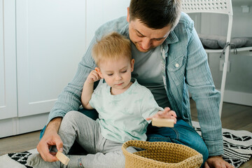 Wall Mural - Happy father and toddler boy child little son playing with wooden blocks in children room at home