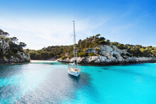 Beautiful Beach With Sailing Boat Yacht, Cala Macarelleta, Menorca Island, Spain. Yachting, Travel And Active Lifestyle Concept