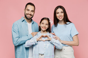 Wall Mural - Young parents mom dad with child kid daughter teen girl in blue clothes show shape heart with hands heart-shape sign hug isolated on plain pastel light pink background Family day parenthood concept.