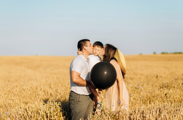 Baby shower party in a field or meadow. Man, woman and child holding a black balloon on gender party. Celebration. Pregnancy. Family. Parenthood concept. Baby Shower.