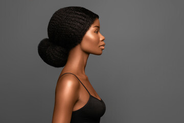 Wall Mural - young beautiful african american model with bun hair profile portrait against grey background.