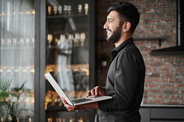 Wall Mural - business owner with a laptop standing in his store.