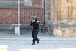 Człowiek z karabinem kałasznikow w czarnym ubiorze idzie ulicą.