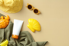 Flat Lay Sun Protection Cream For Babies And Toddlers With Towel, Kids Sunglasses, Panama Hat, Sandbox Toys On Beige Background. Sunscreen Lotion For Kids