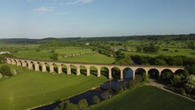 View Along Arthington Viaduct And River Wharfe With People Walking In The Fields Near Otley In The Yorkshire Countryside. Drone Aerial
