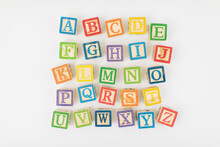 An Arrangement Of Children Painted Alphabet Wooden Blocks Isolated With White Background For Text Copy Space. 