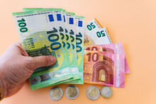 Woman's Hand Holding Various Euro Banknotes On Orange Background