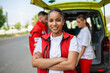 © Graphicroyalty - Young female african american paramedic standing rear of the ambulance. paramedics by the ambulance. Two paramedics taking out strecher from ambulance