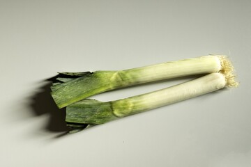 Two leeks isolated on gray background, Allium ampeloprasum, porrum