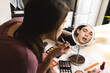© Wavebreak Media - Non-binary trans woman putting lipstick looking in the makeup mirror at home