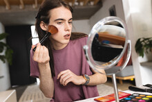Non-binary Trans Woman Doing Makeup With Blusher Brush Looking In The Makeup Mirror At Home