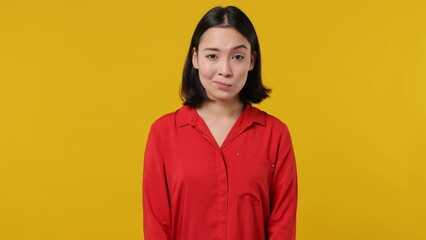 Wall Mural - Secret fun young woman of Asian ethnicity 20s wears red shirt look aside say hush be quiet with finger on lips shhh gesture isolated on plain yellow background studio portrait. People emotions concept
