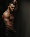 Dark portrait of shirtless bearded fitness man in jeans
