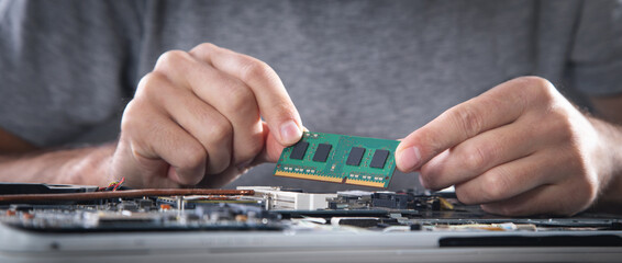 technician installing random access memory on laptop computer.