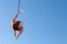 A Young Trapeze Artist Suspended In Mid-air Attached To A Circus Hoop
